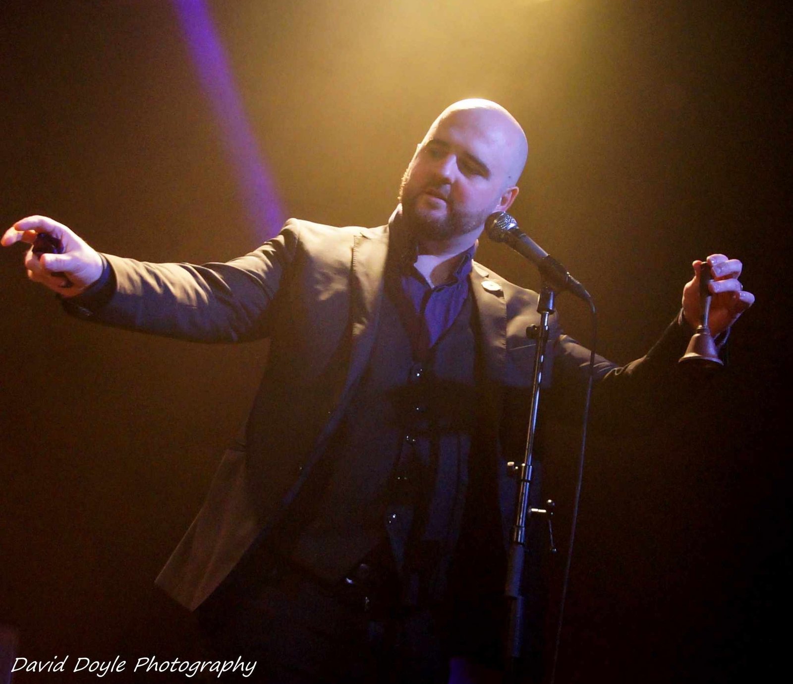 David Peace on stage mid performance with his arms outstretched