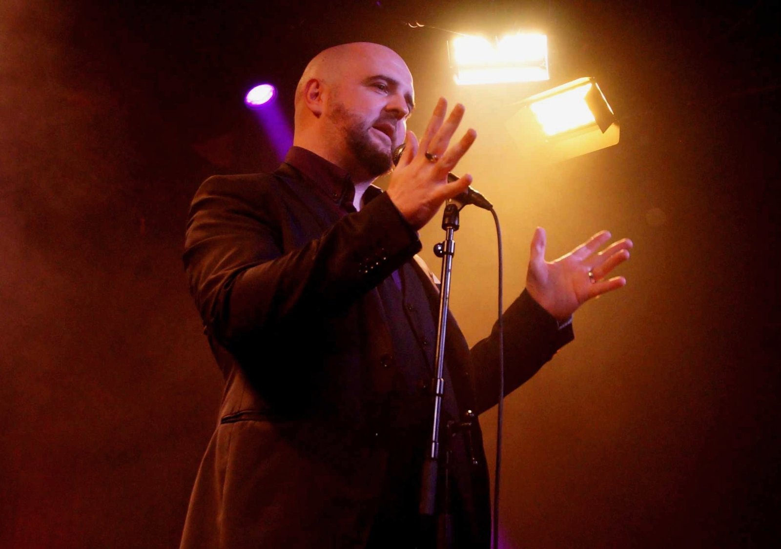 David Peace performing on stage with a microphone